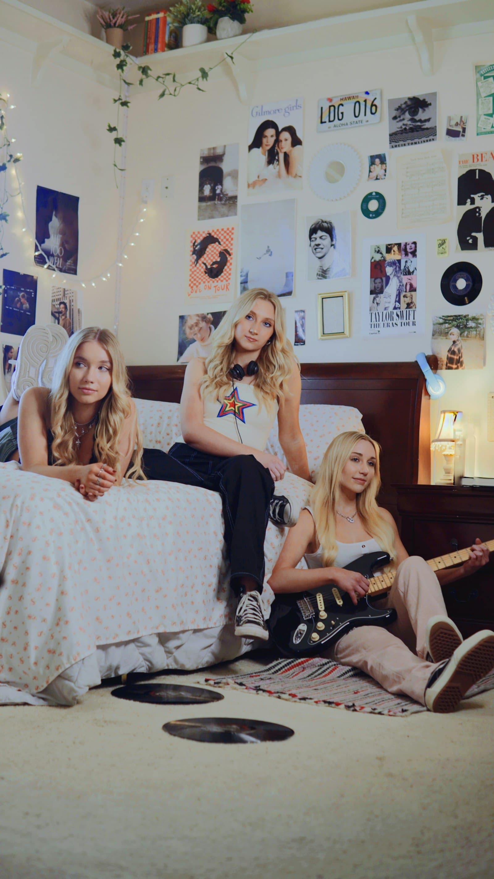 Three friends hanging out in a dorm room covered in posters
