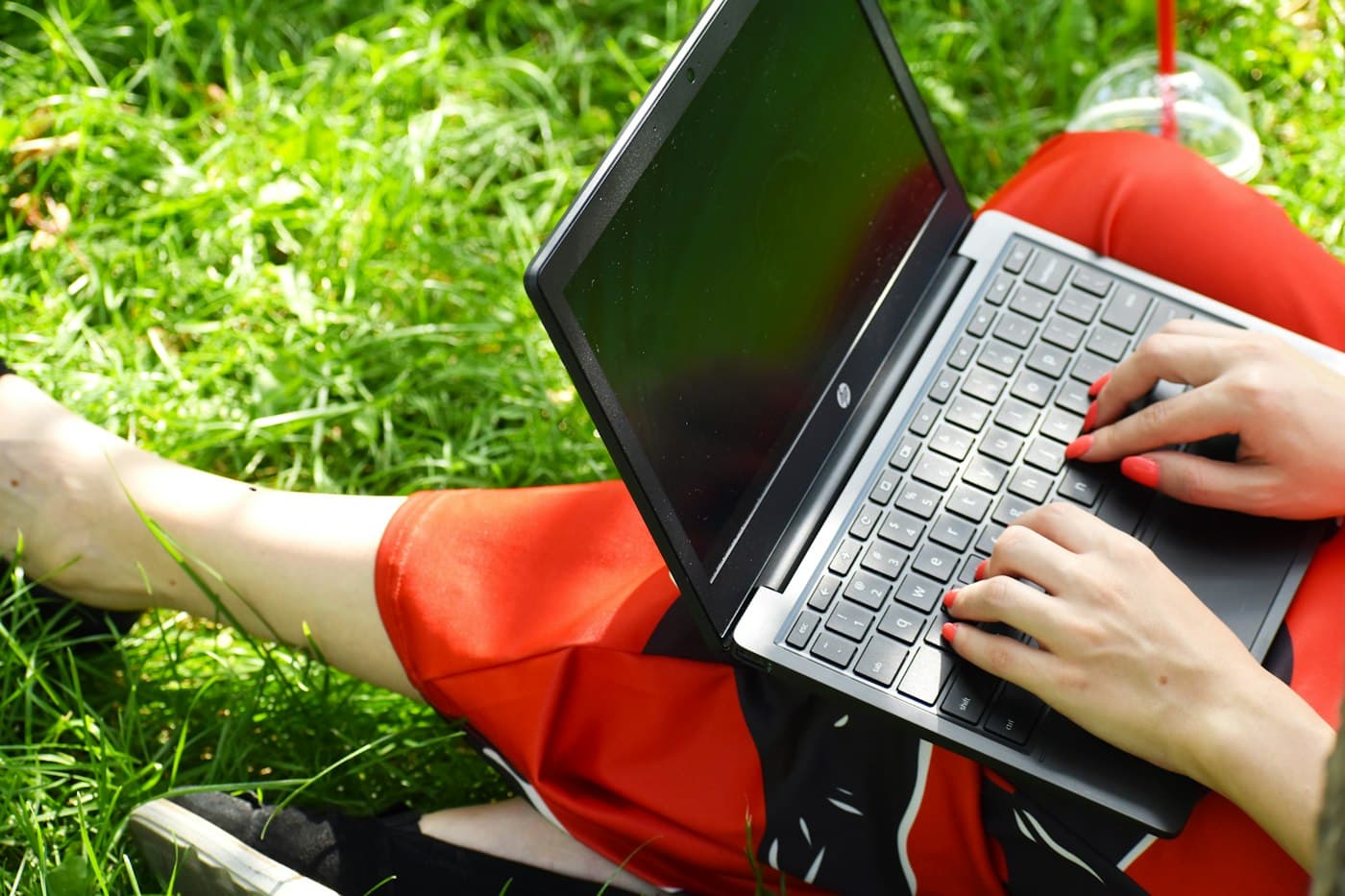 Doing homework on a laptop while sitting on the grass