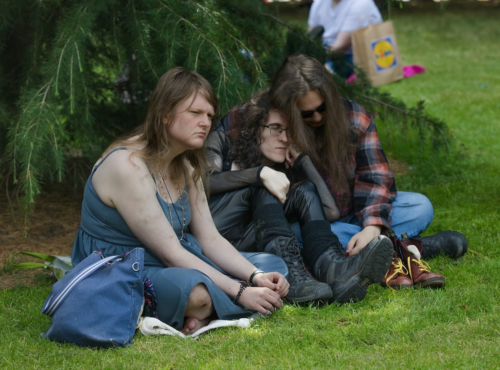 Three friends sitting on the grass under a tree